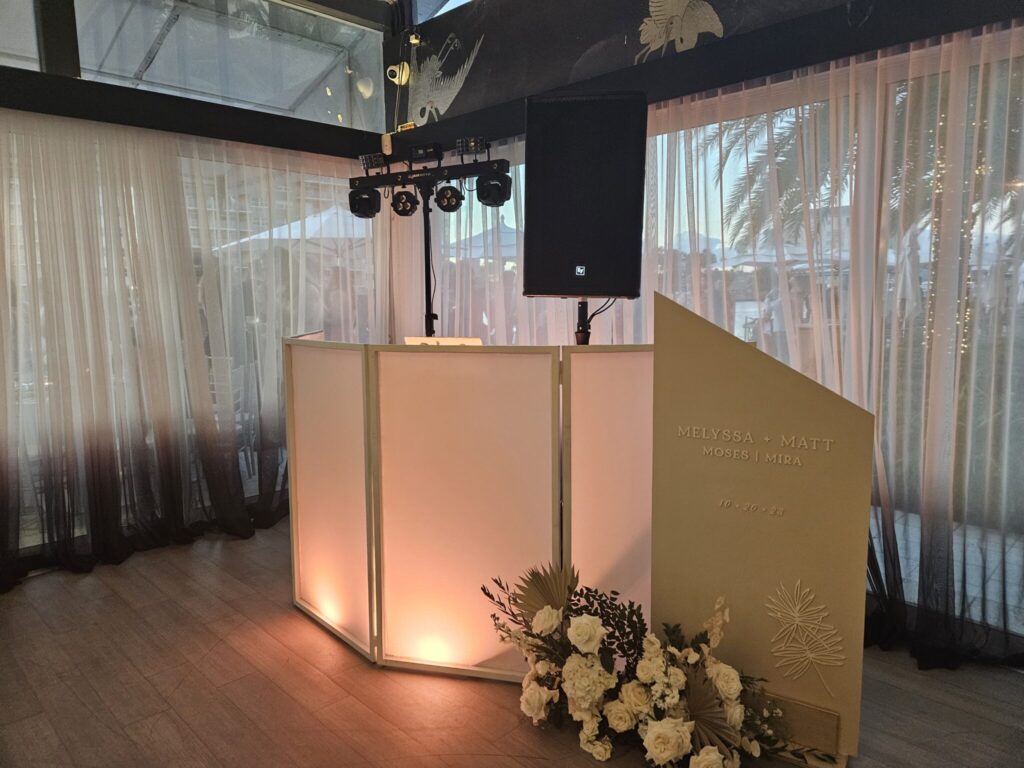 Sleek illuminated DJ booth with floral accent for custom wedding sound service in Boca Raton, FL