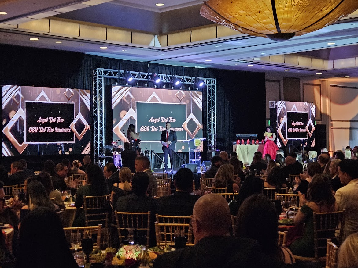 Corporate event DJ and stage presentation in Hollywood, FL featuring large LED video screens, truss lighting, and a seated audience gala