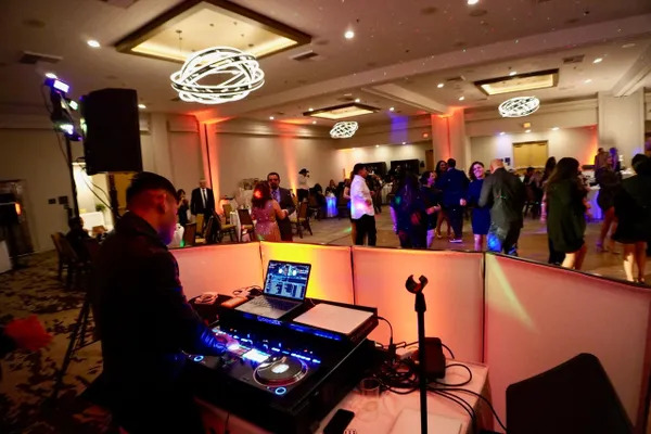 Private Event DJ Service In Boca Raton, FL 2 Event DJ mixing tracks behind illuminated partition during ballroom celebration in Boca Raton, FL