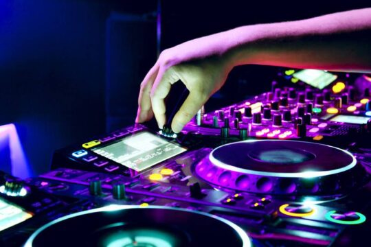Close-up of event DJ adjusting glowing audio mixer controls in Weston, FL