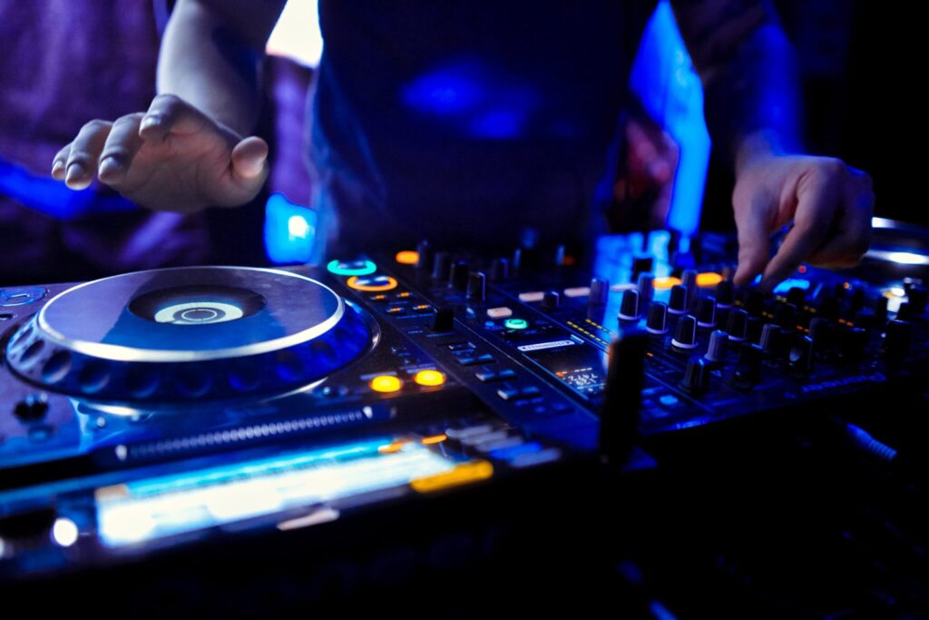 Professional DJ mixing tracks on illuminated Pioneer audio equipment at an event in Fort Lauderdale, FL